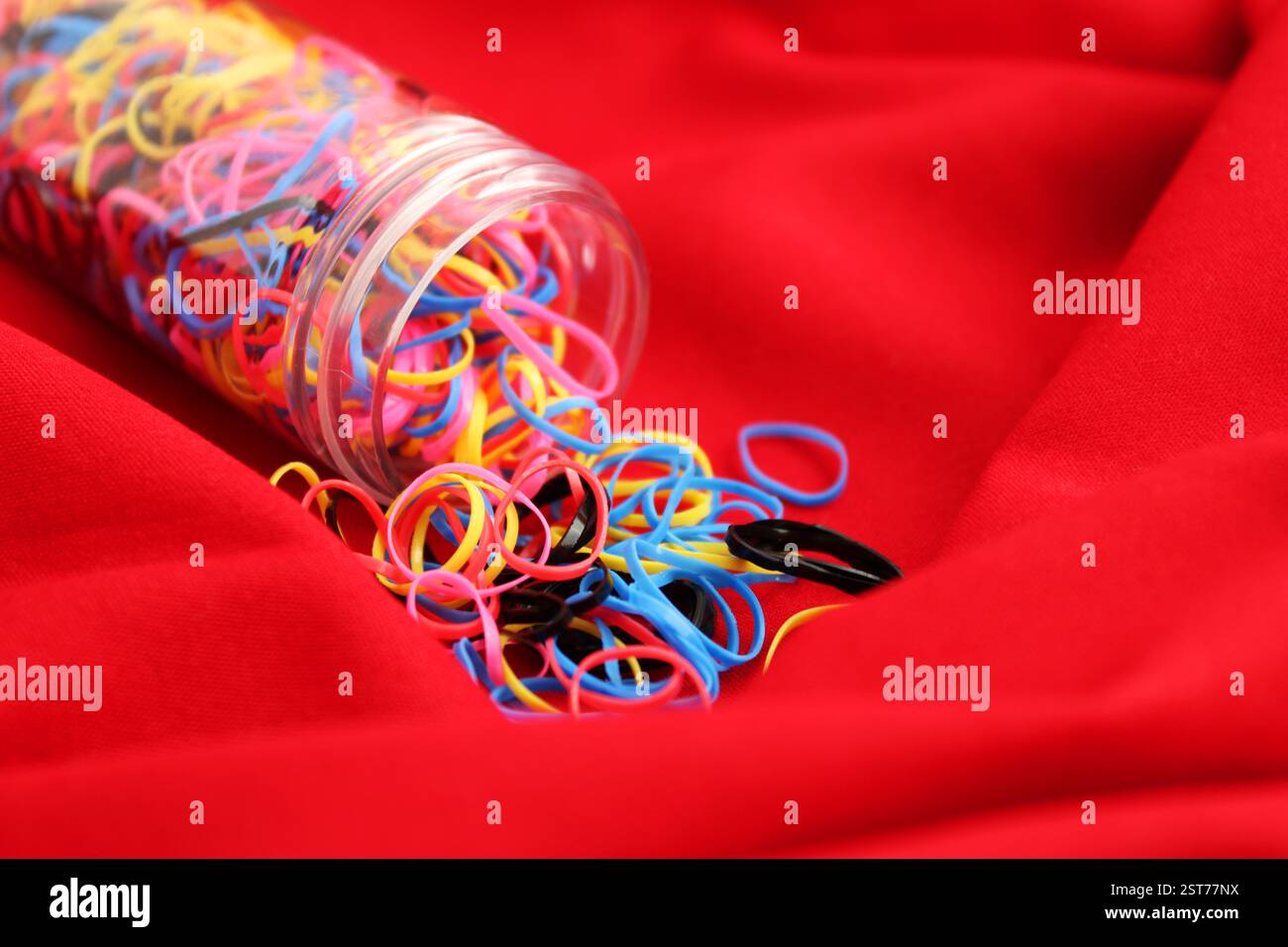 Many elastic bands come out of tubular container Stock Photo