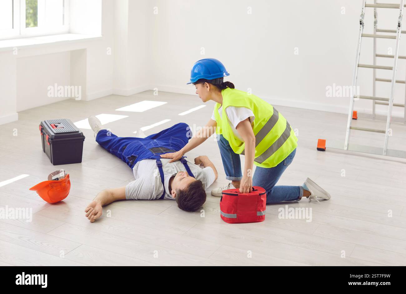 Worker Administers First Aid with Workplace Kit to Colleague After Accident Stock Photo
