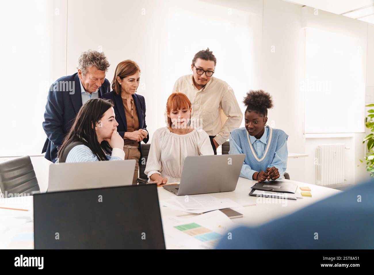 Diverse startup team discussing an innovative business strategy in a modern office. Concept of entrepreneurship, tech development, and creative collab Stock Photo
