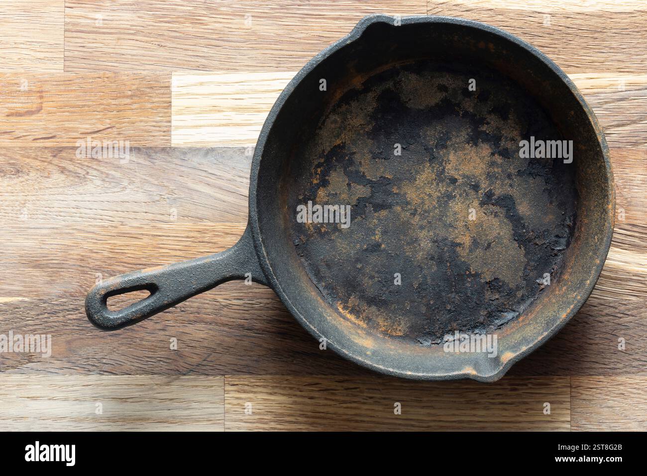 Old rusty cast iron frying pan background. On a wooden chopping cutting board. Stock Photo