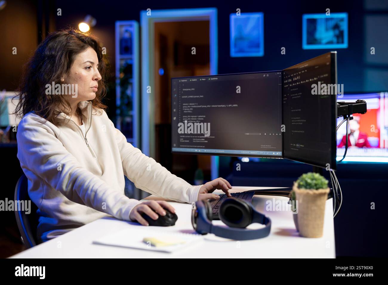 Computer scientist doing software debugging on PC at home, checking broken lines of code displayed on monitors. Skilled IT expert in apartment fixing coding problems, typing on keyboard Stock Photo
