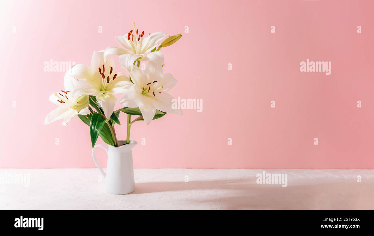 White lilies in a ceramic vase on a pastel pink background with soft ...