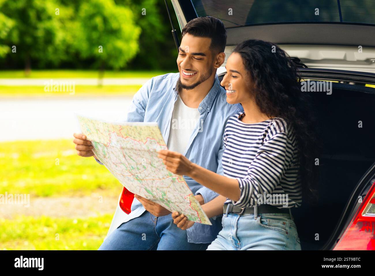 Loving middle-eastern couple watching map while having break, copy space Stock Photo
