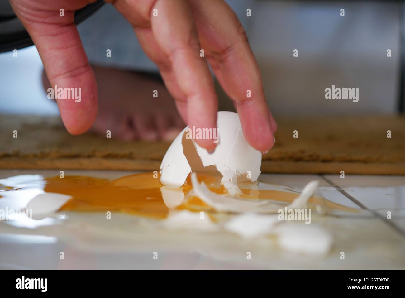 Egg shell cracks on kitchen floor after accidental drop during cooking Stock Photo