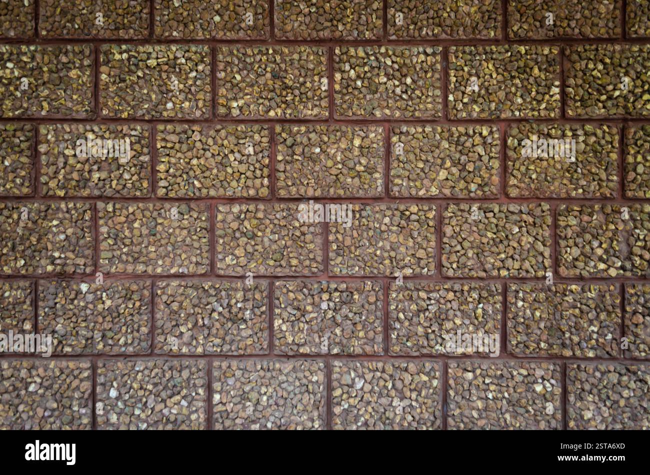 Textured brown exposed aggregate stone block wall texture pattern background. Stock Photo