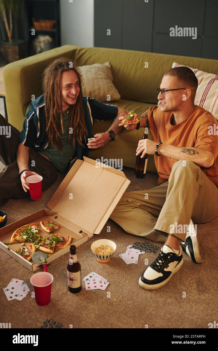 Enjoying Pizza and Drinks while Having Fun with Cards Stock Photo