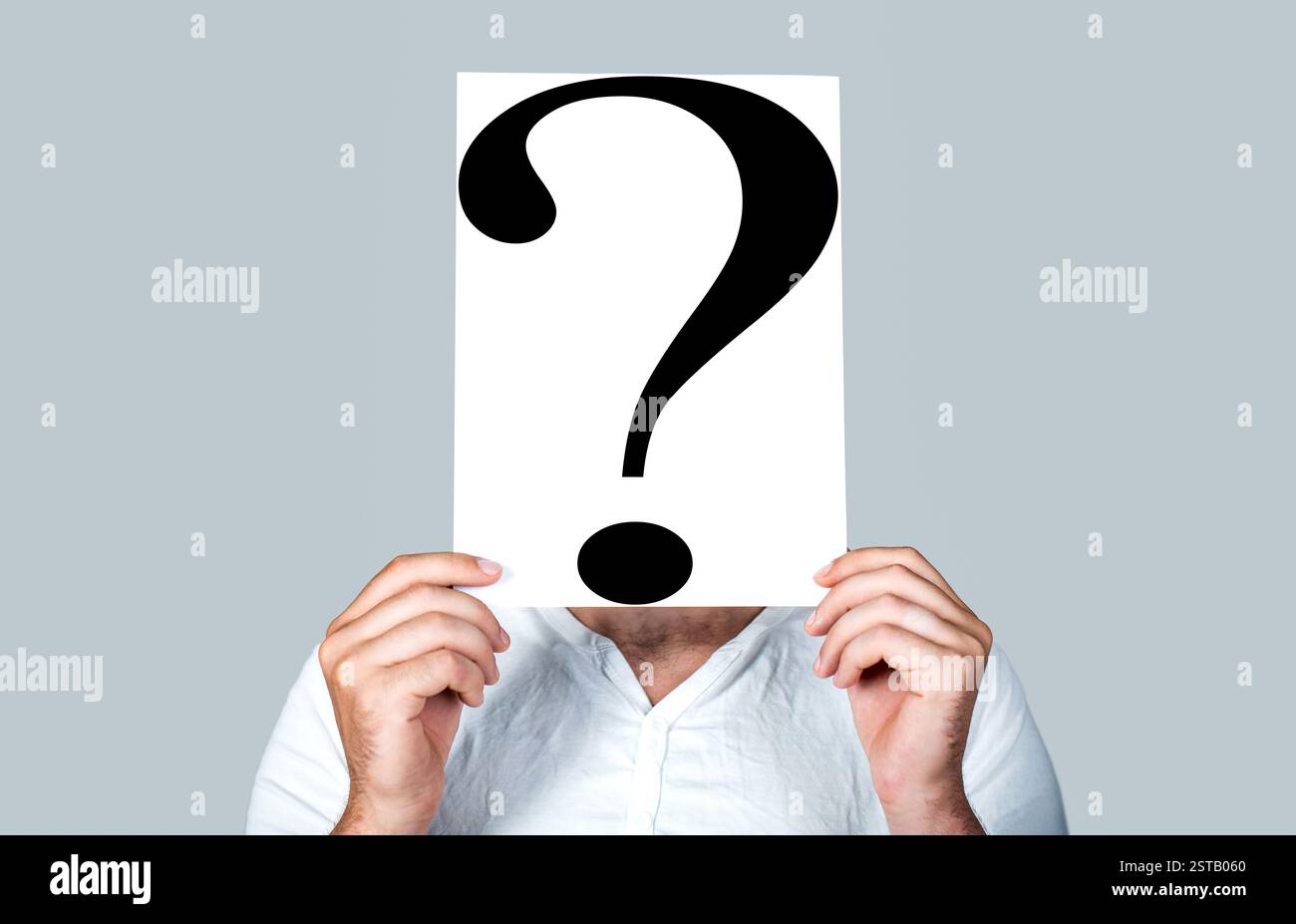 Man holding question mark sign on light background. Portrait of man ...