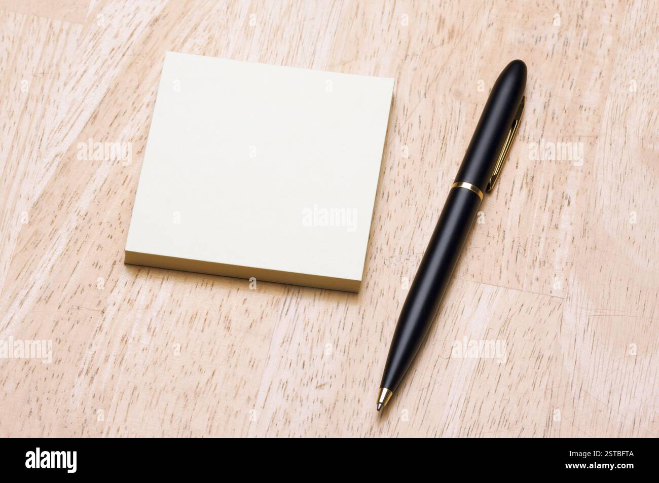 Pen and Post It Notes Pad Against a Wood Background Stock Photo