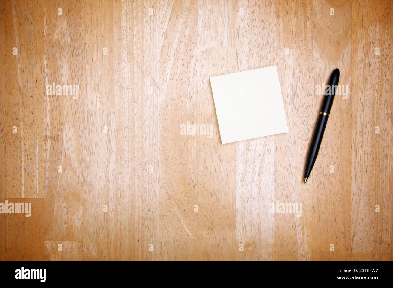 Pen and Post It Notes Pad Against a Wood Background Stock Photo