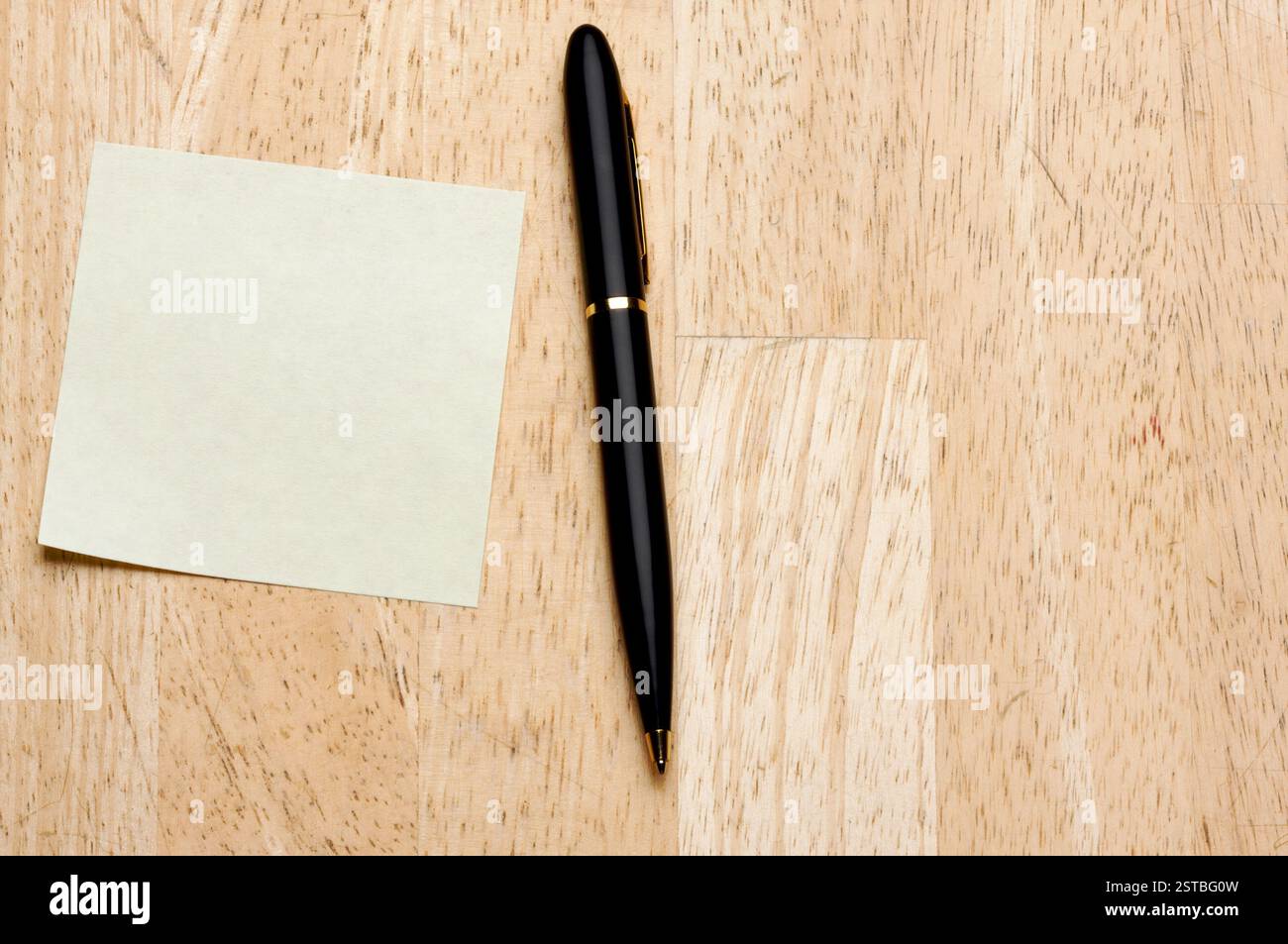 Pen and Post It Notes Pad Against a Wood Background Stock Photo