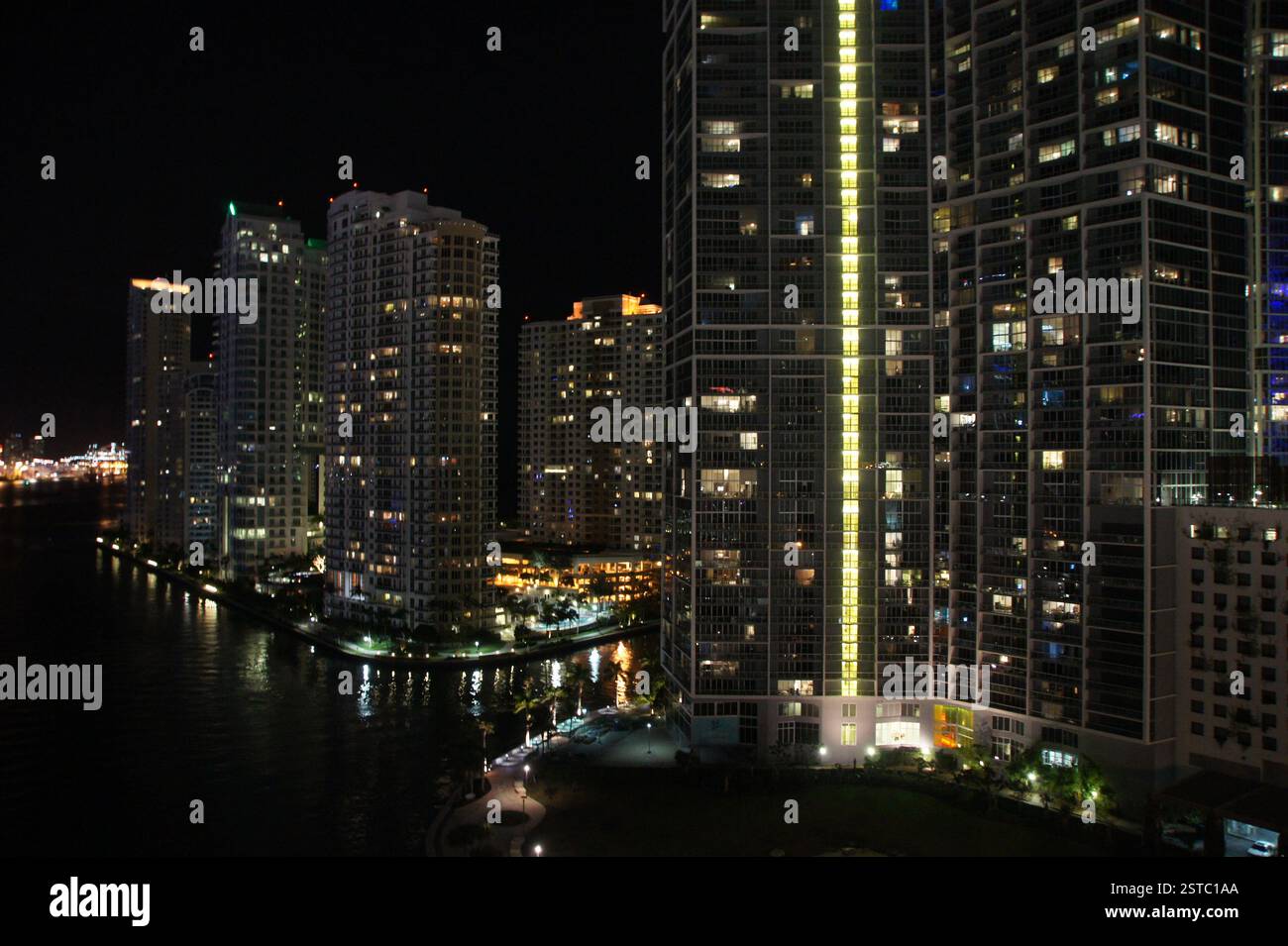 Miami skyline at night, tall buildings line riverbanks, illuminated in ...