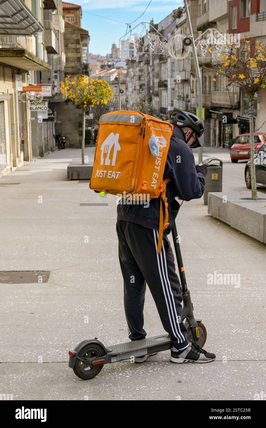 Vigo, Spain - 14 January 2025: Delivery person with an electric scooter  working for Just Eat checking his phone Stock Photo - Alamy