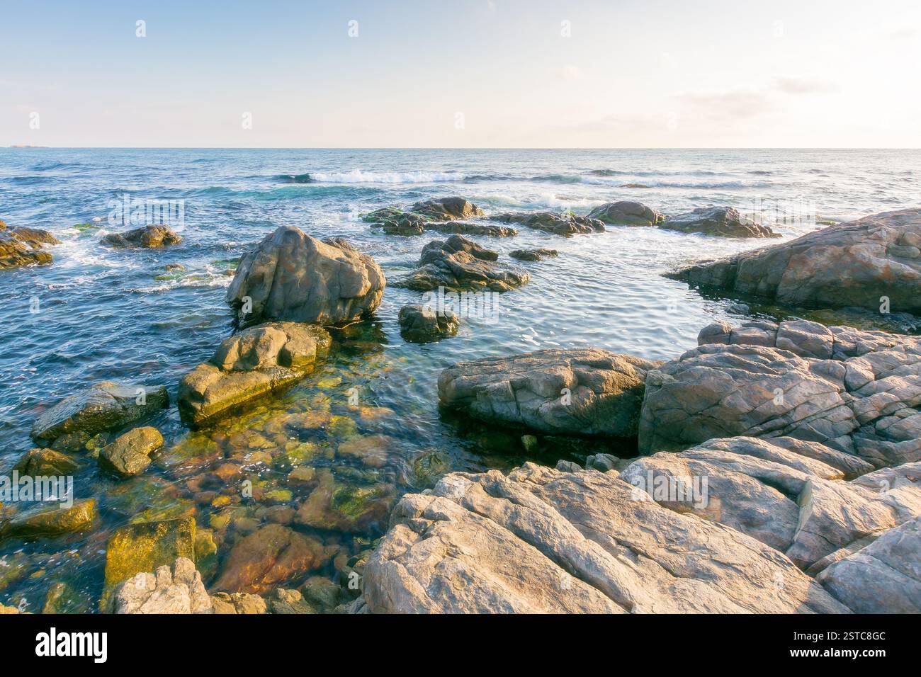 beautiful sunrise at the black sea. wide open horizon. rocky coast and clouds on the blue sky in morning light. summer vacations and weather change co Stock Photo