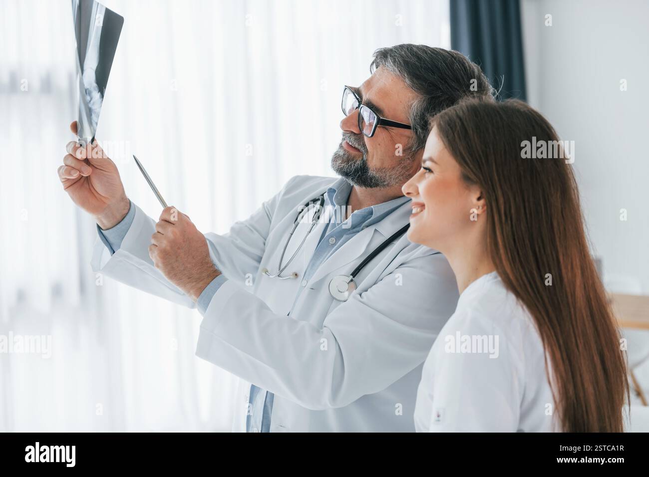 Looking at x-ray. Professional medical workers in white coats is in the office. Stock Photo