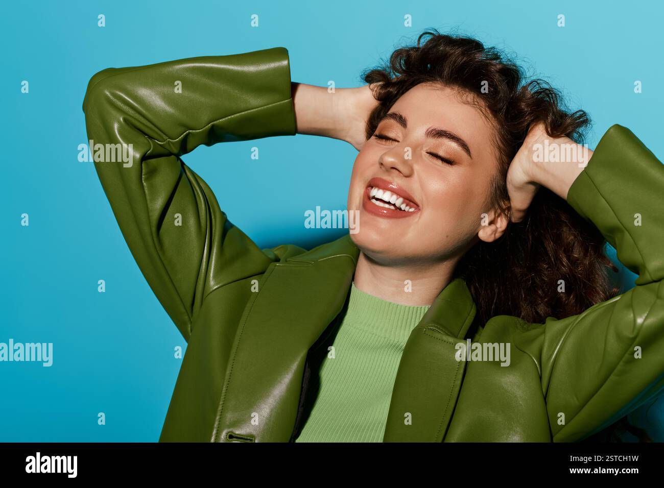 A beautiful young woman with curly hair smiles joyfully while posing in ...