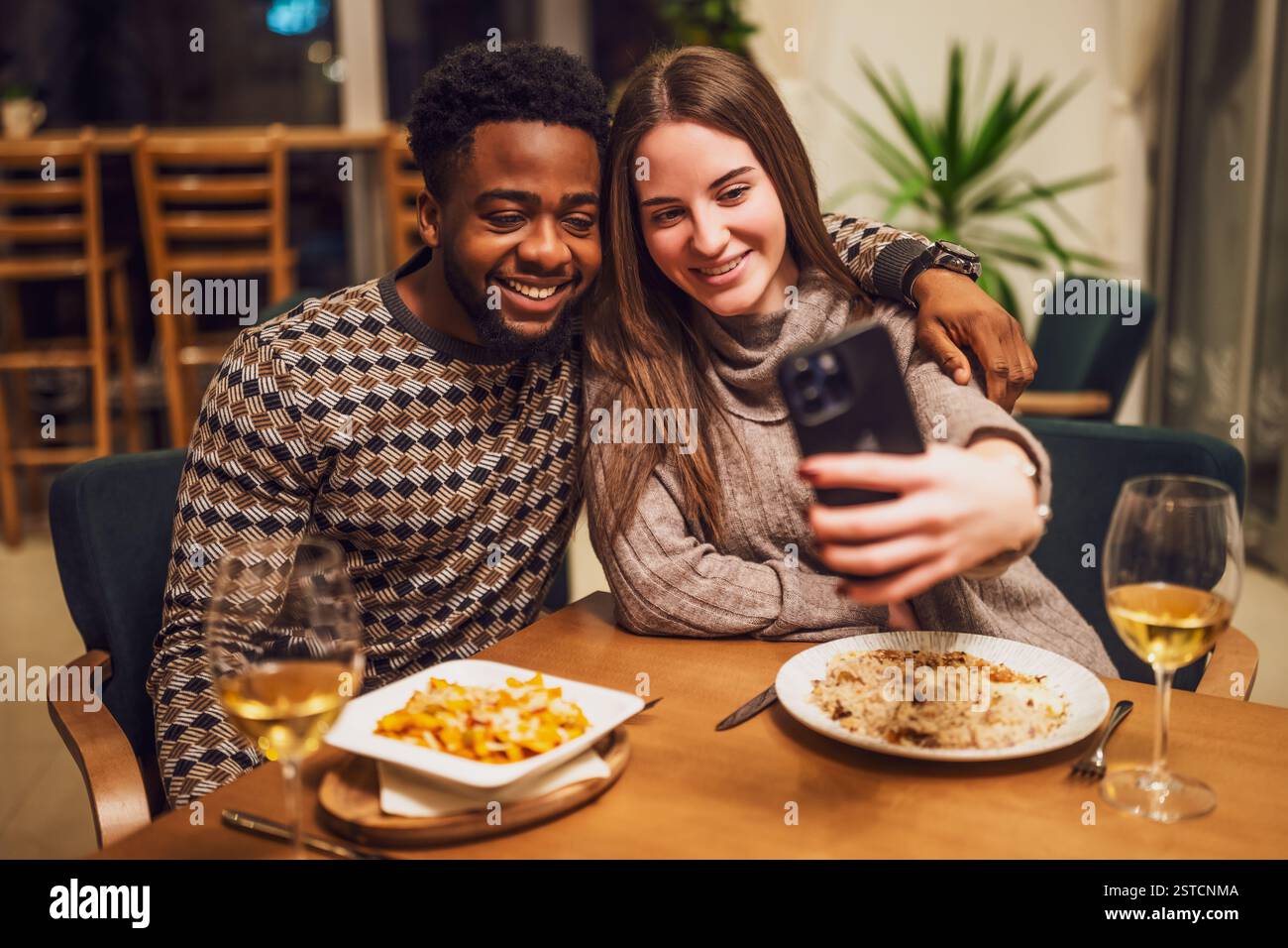 Two friends are having dinner at restaurant. They are taking selfie. Stock Photo