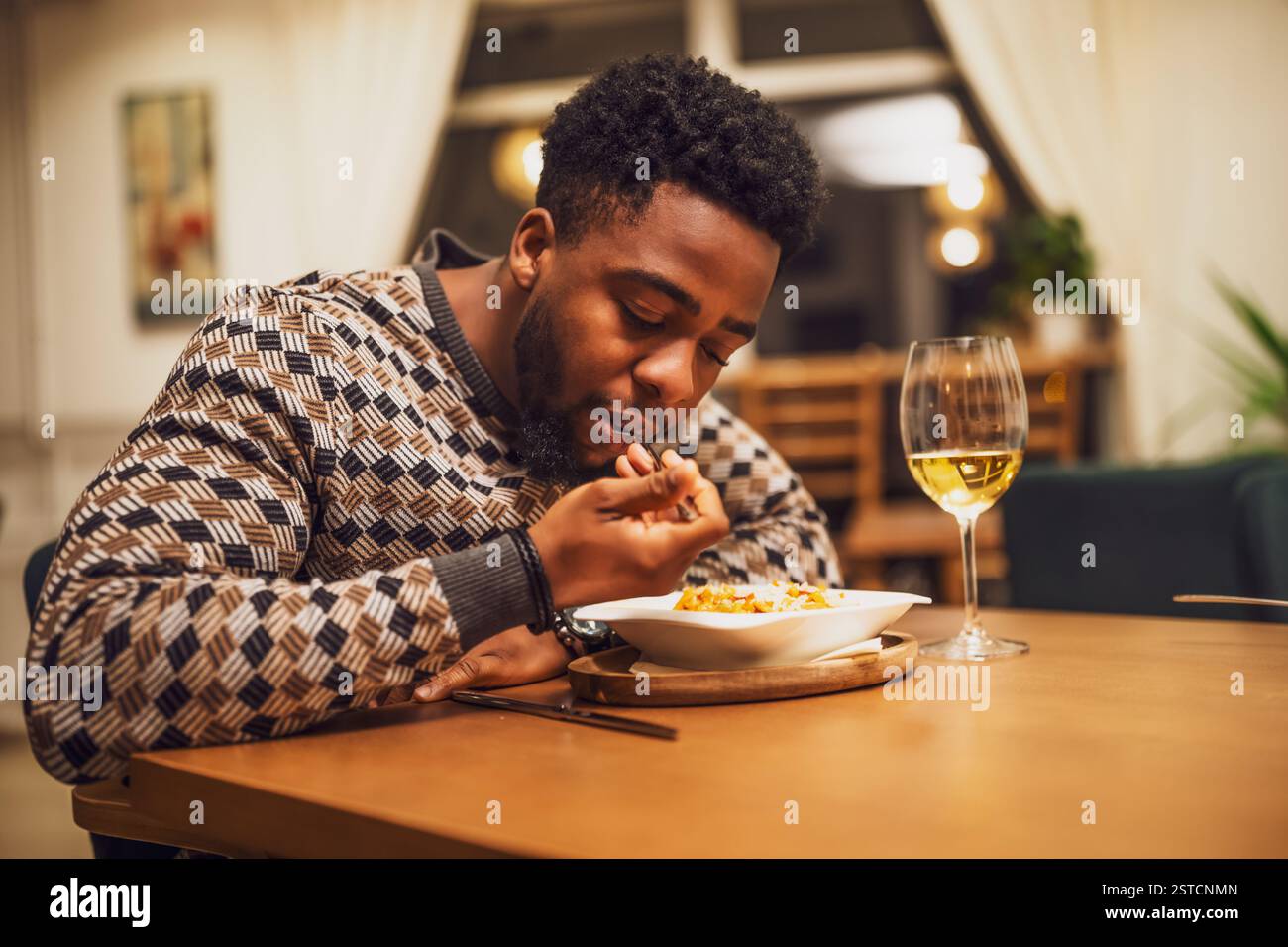 Young black man is having dinner and wine at restaurant. Stock Photo