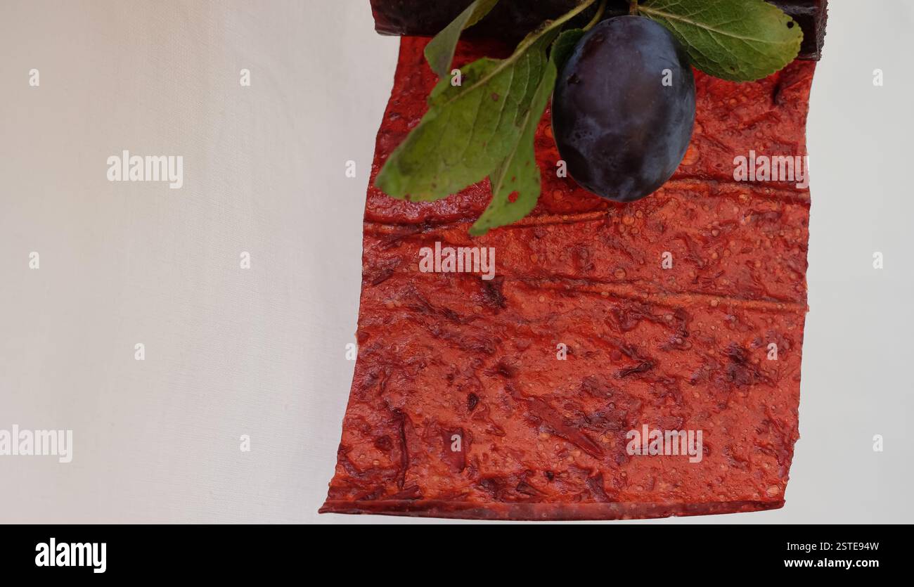Plum pastille or fruit leather on a white background. Blurred plum. Copy space. Stock Photo