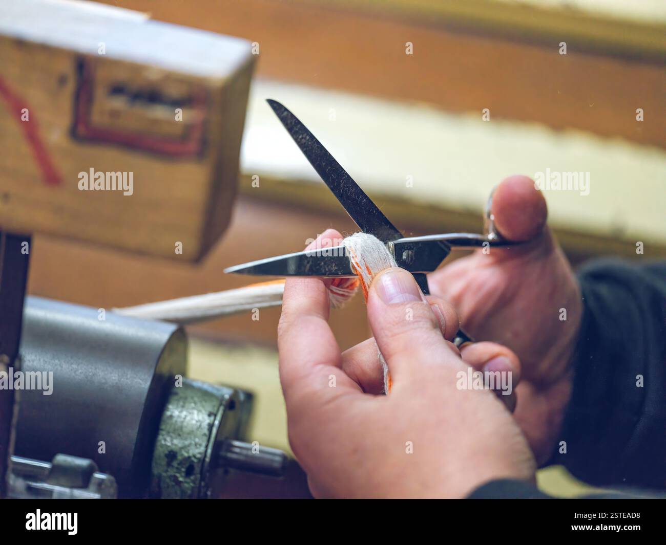 Close-up of a worker's hands trimming yarn with scissors at a textile ...