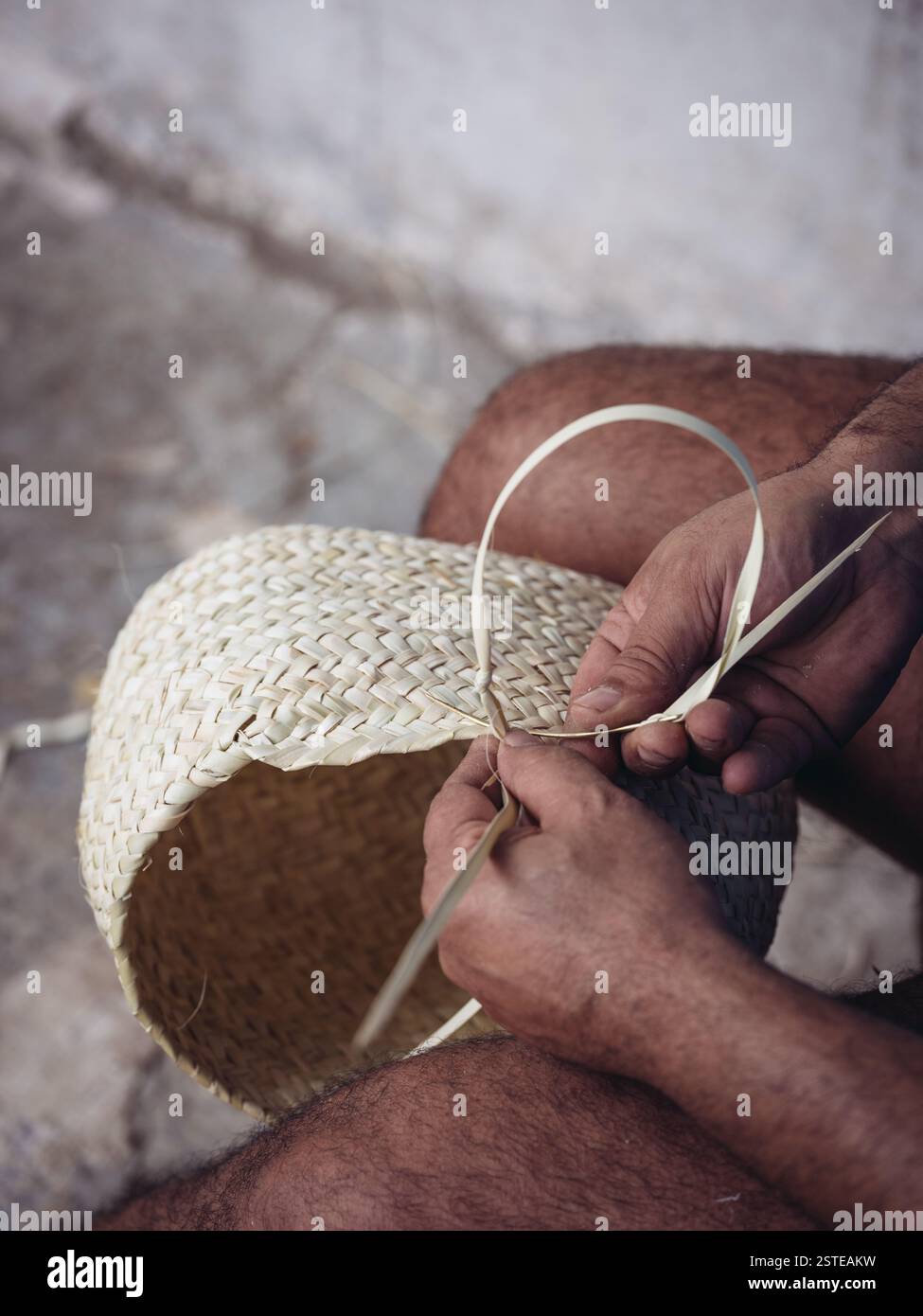 Close-up of the hands of an artisan weaving a basket with palmetto ...
