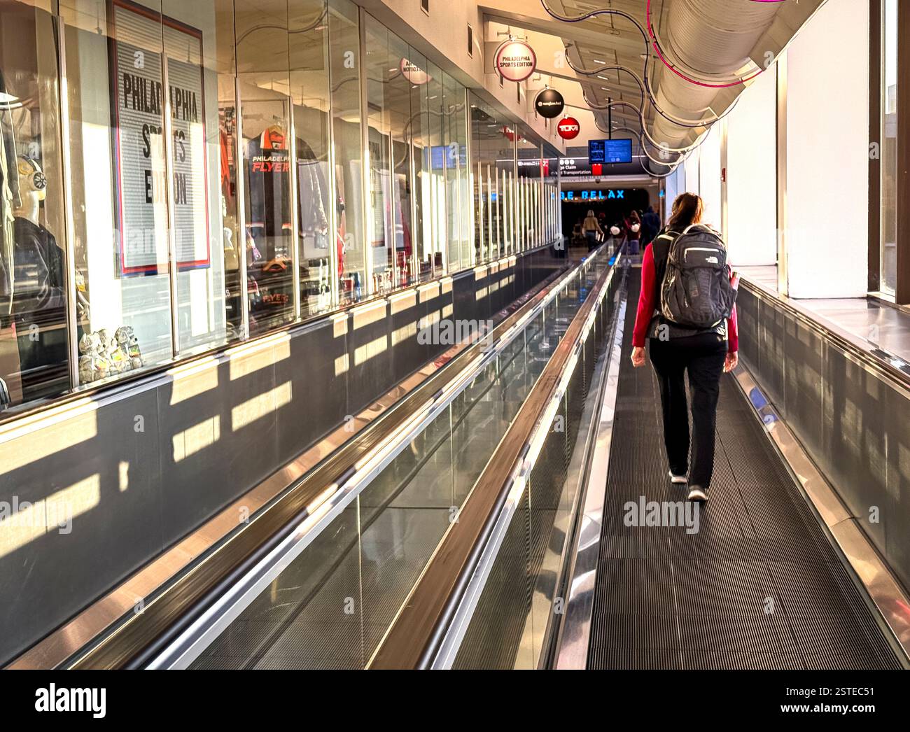 Woman walks to her gate with the assistence of a conveyor belt. Stock Photo