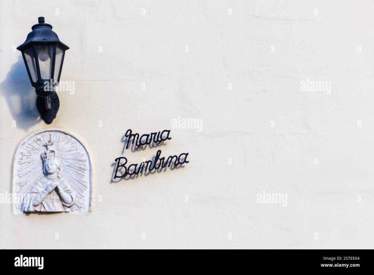 Wall Shrine of Mary with Decorative Lamp on a White Plaster Background Stock Photo