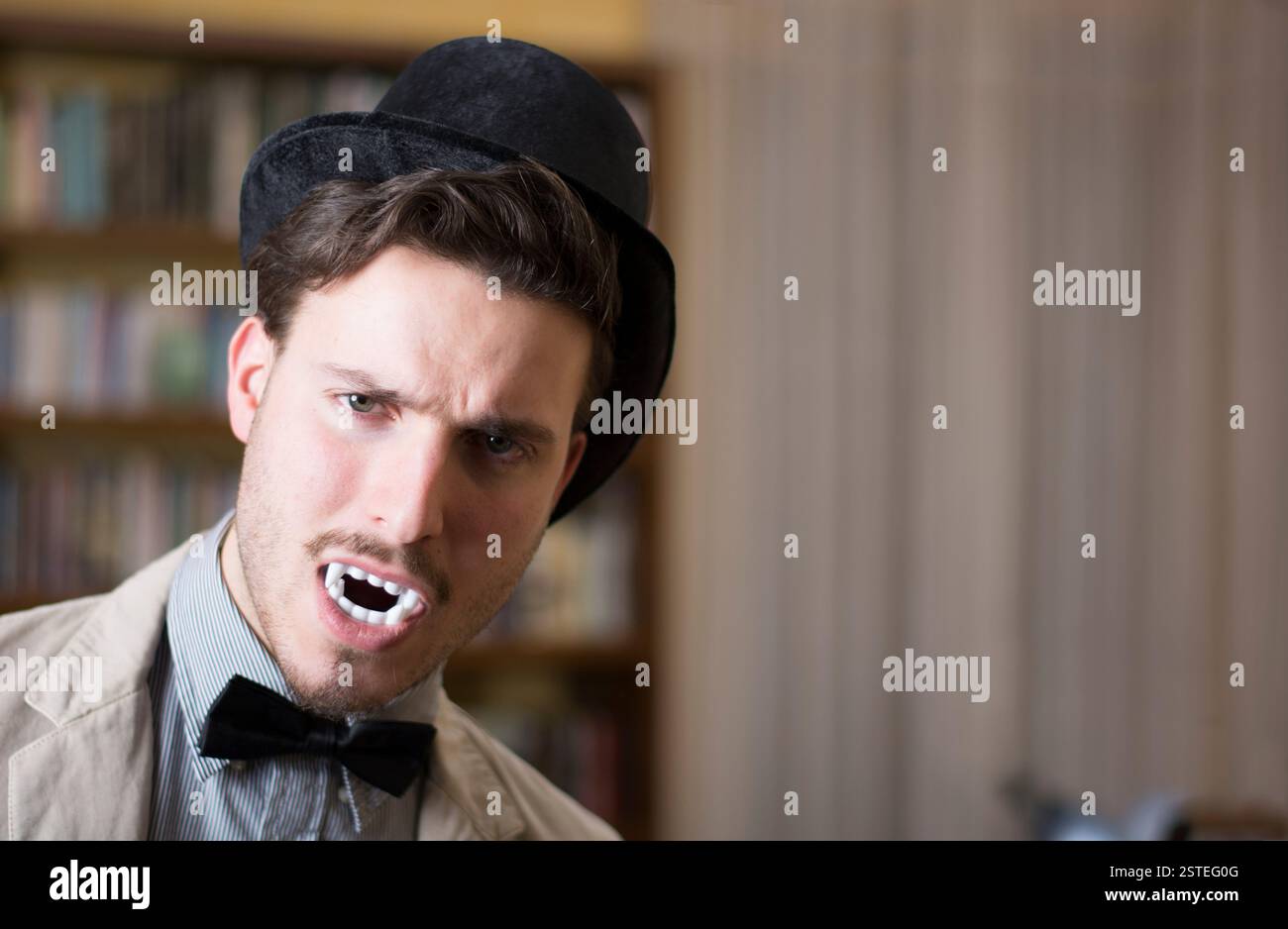 Close up Young Handsome White Vampire with Black Top Hat Inside the Mini Library Stock Photo