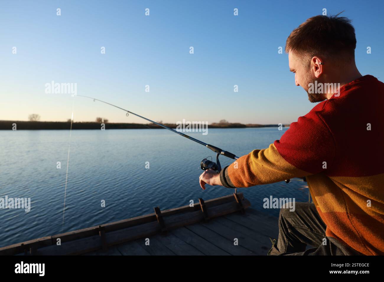 Fisherman with fishing rod at riverside on sunny day Stock Photo - Alamy
