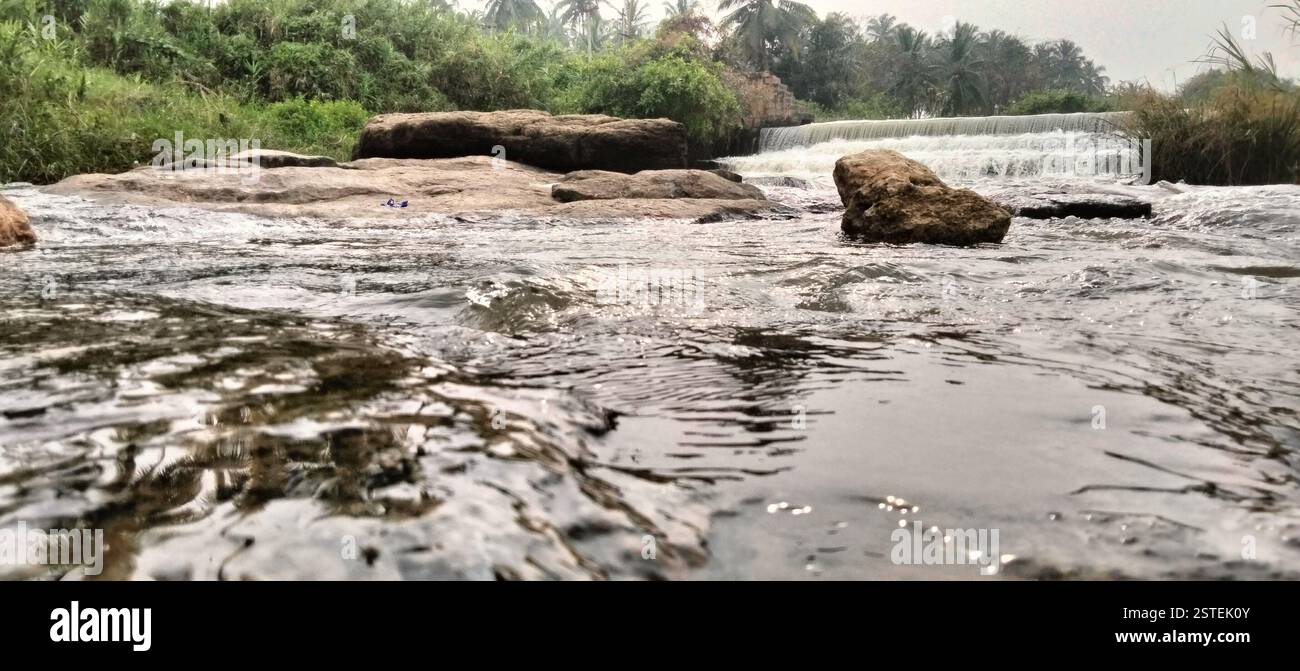 Dam spillway with strong water flow crashing onto rocky riverbed. - Smartphone Captured Stock Image