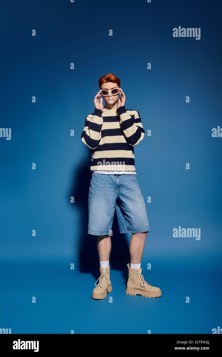 Emotional young man in stylish outfit stands confidently in front of a ...