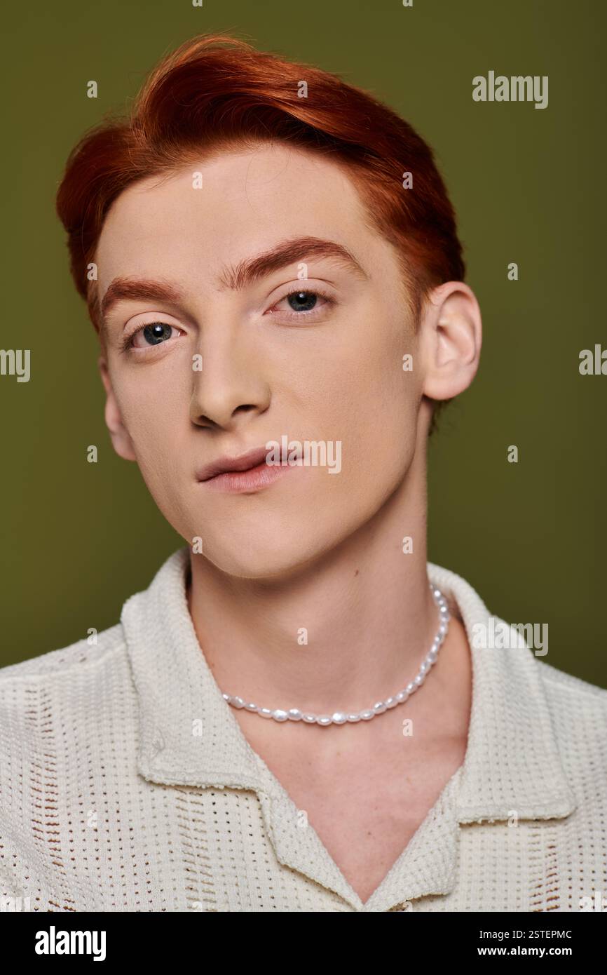 A handsome young man with red hair conveys profound emotions against a subtle green backdrop. Stock Photo
