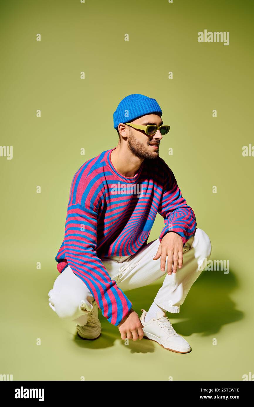A young man in a stylish, colorful outfit poses confidently in a studio ...