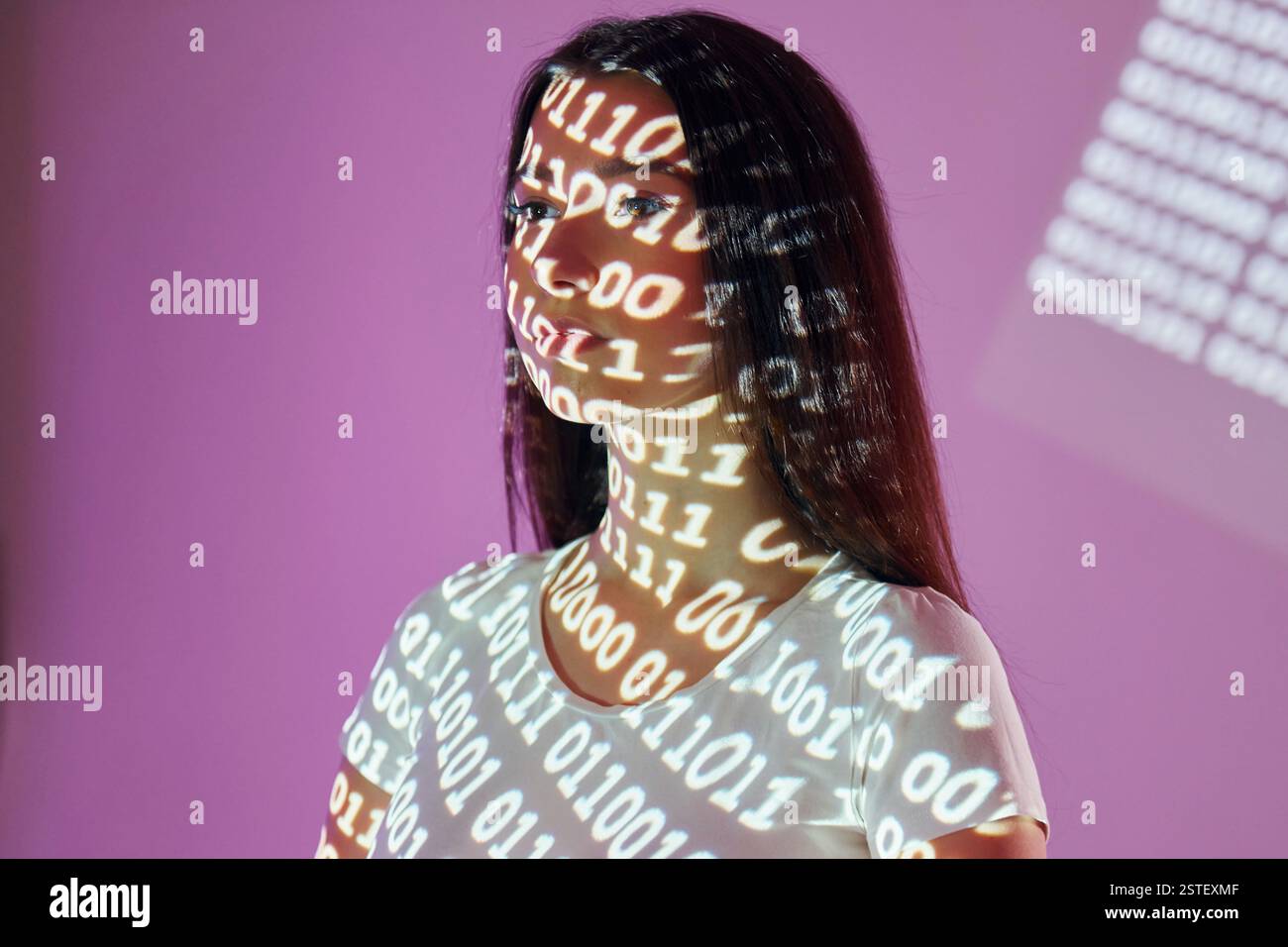 Binary machine code. Beautiful young woman is in projector neon lights in the studio. Stock Photo