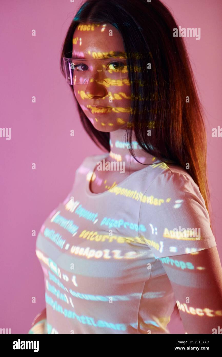 Front end programming language's scripts. Beautiful young woman is in projector neon lights in the studio. Stock Photo
