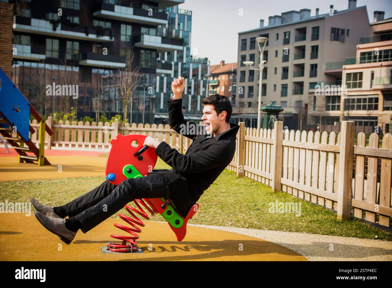 Young man reliving his childhood plying in a children's playground ...