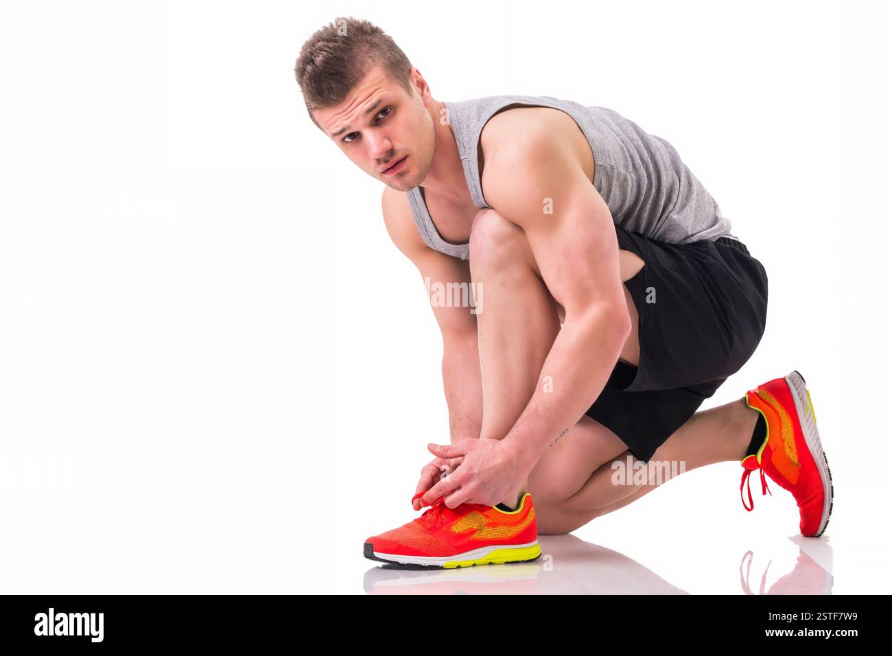 Handsome young man kneeling and tying sneaker Stock Photo - Alamy
