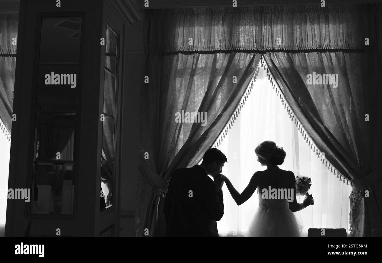 bride and groom standing in front of a large window indoor Stock Photo ...
