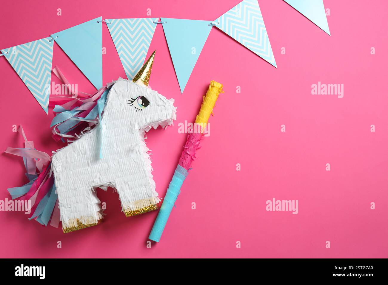 Bright pinata in shape of unicorn and party accessories on pink ...