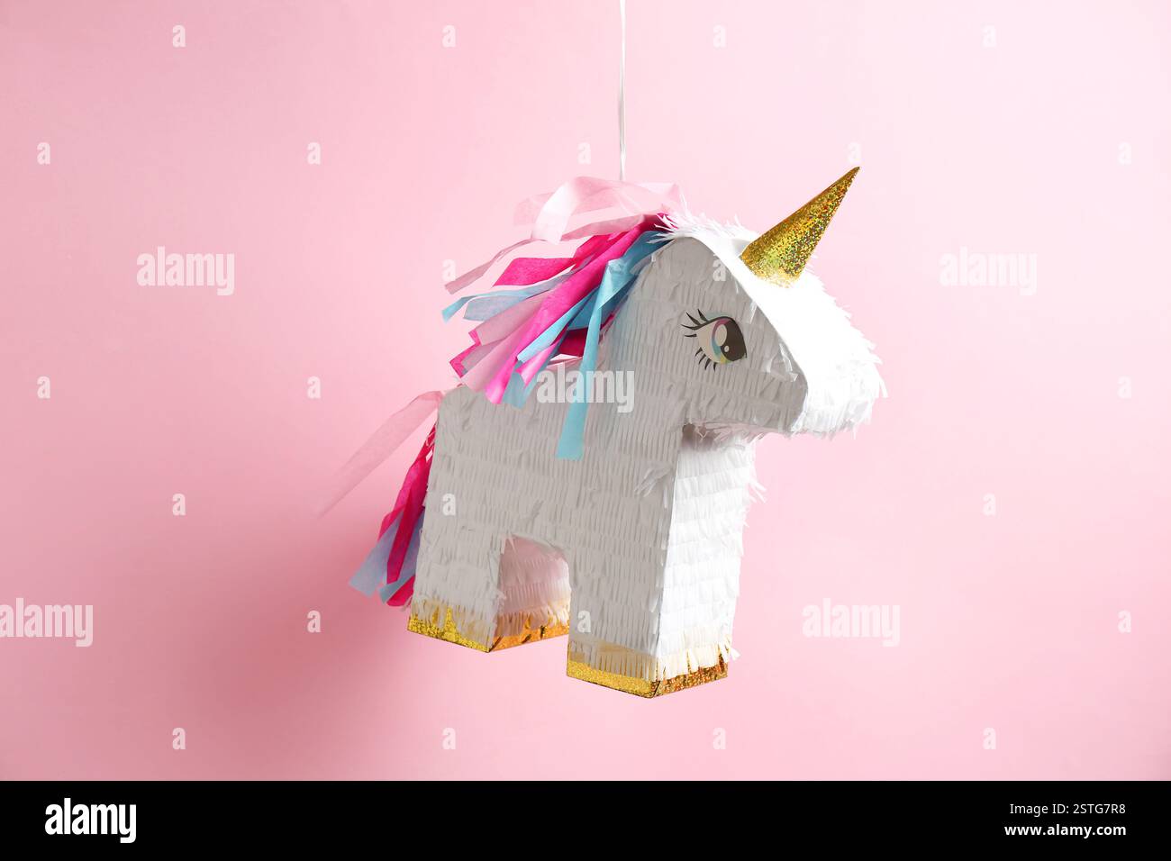 Bright pinata in shape of unicorn hanging on pink background Stock ...