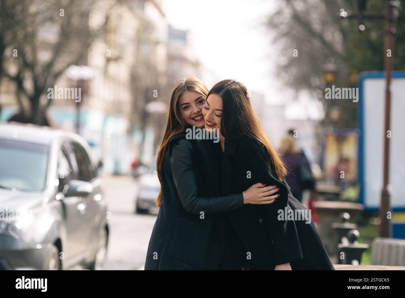 Two young adult women posing on a city street Stock Photo - Alamy