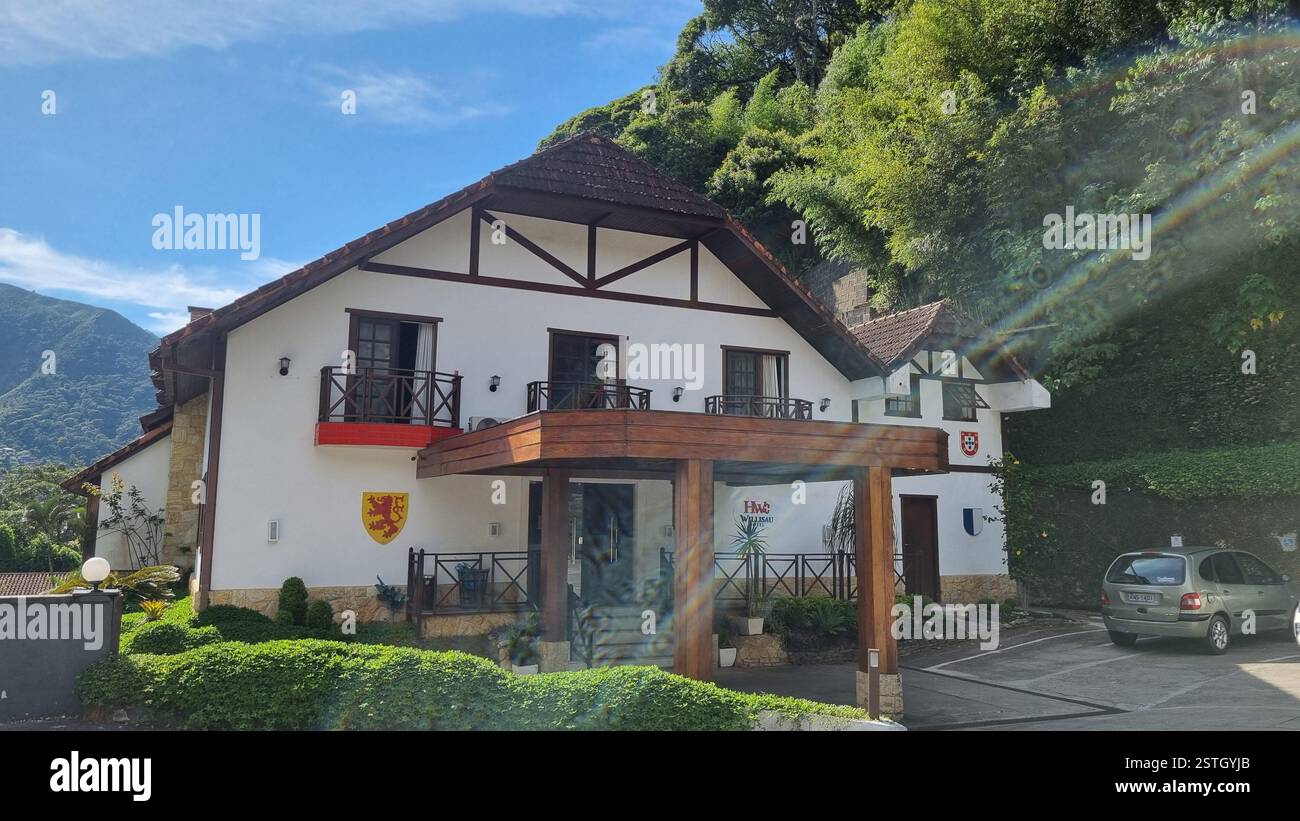 This charming European-style house is nestled at the foot of a lush, green hill, blending nature and architecture beautifully. - Smartphone Captured Stock Image