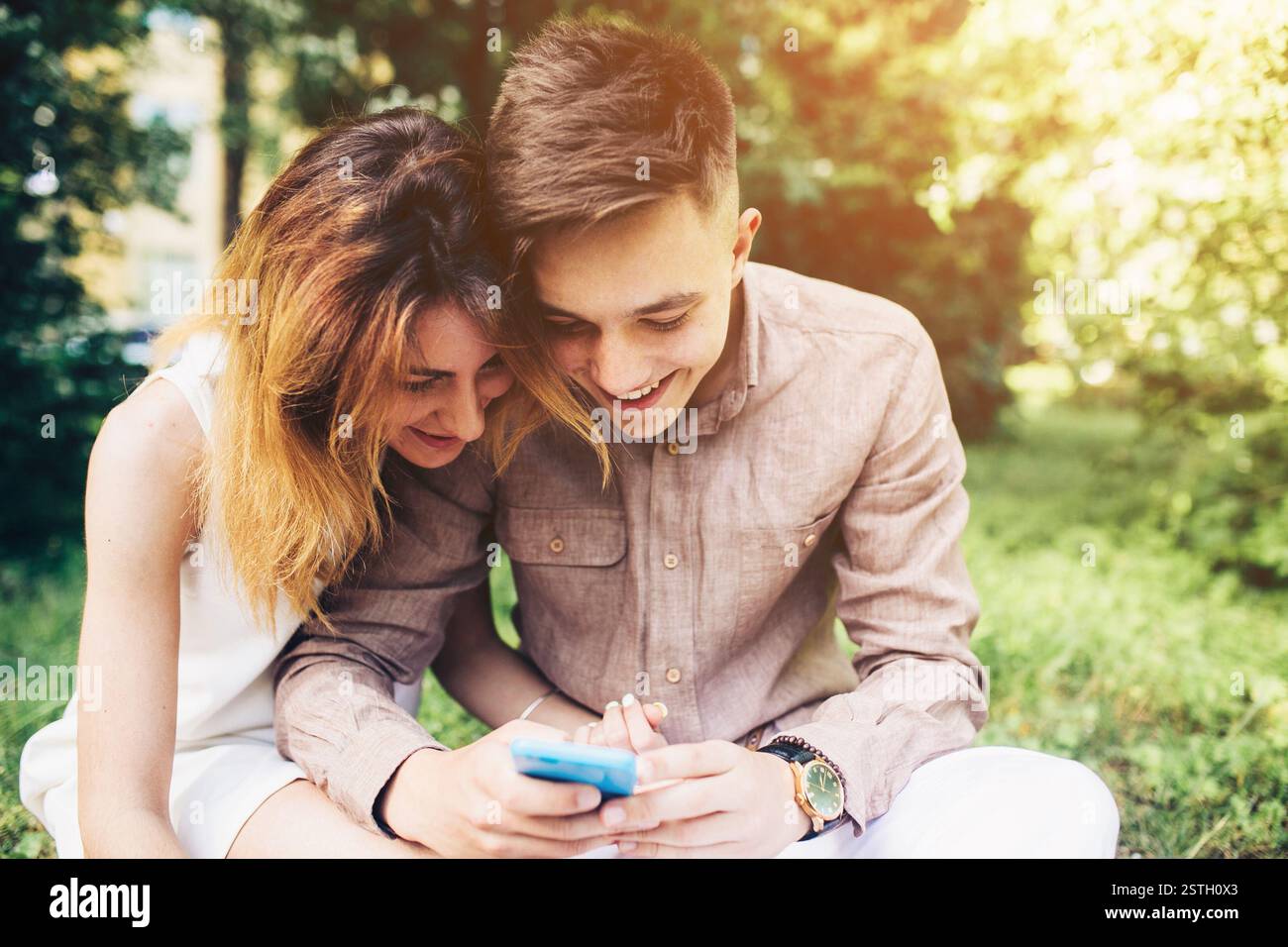 Cople using a smartphone, sitting in the park Stock Photo