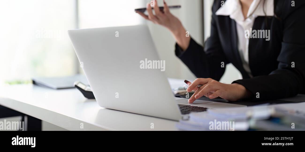 Multitasking financial professional on a call while managing data and calculations in a modern office. Stock Photo