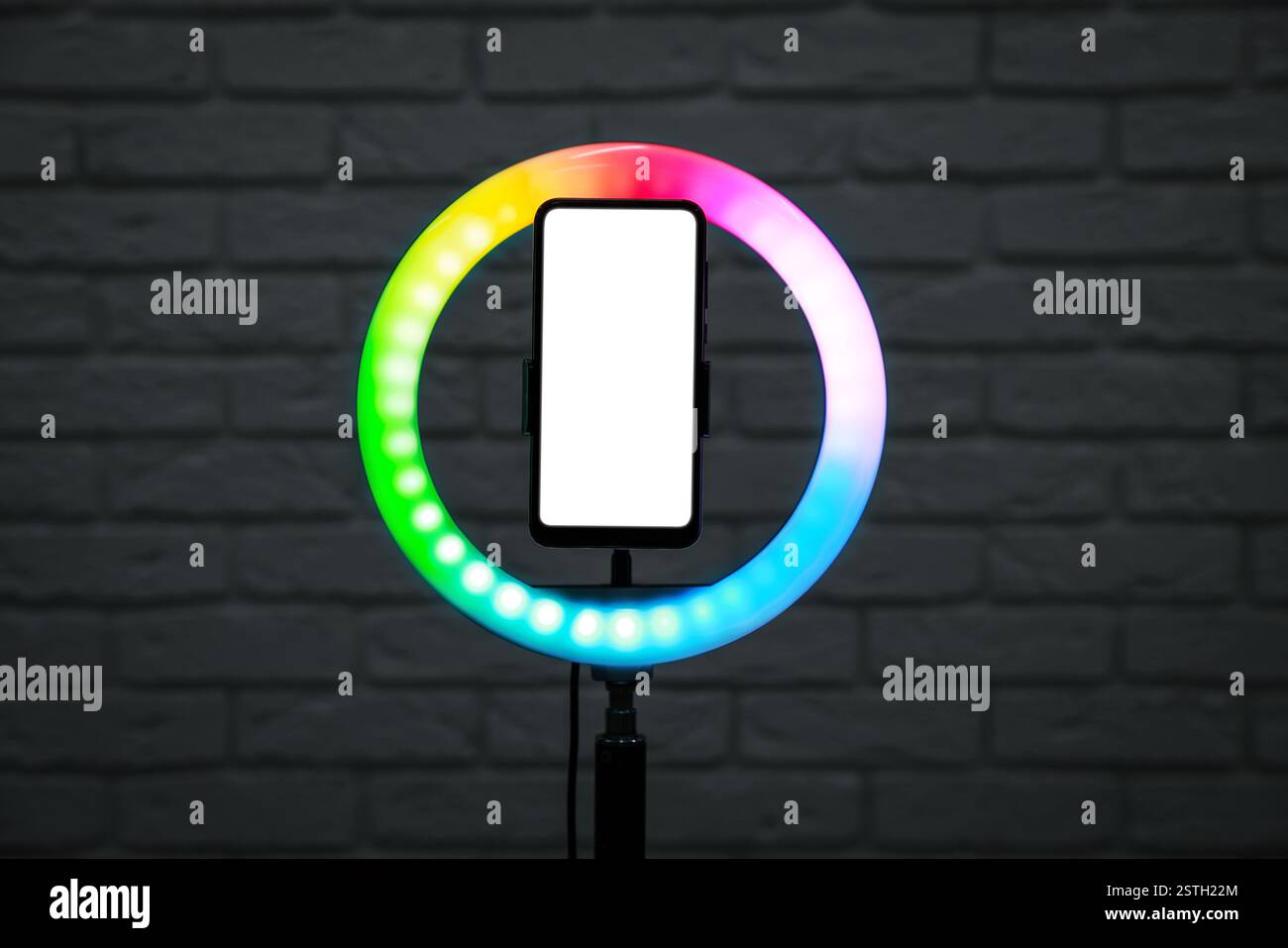Ring lamp with smartphone against brick wall Stock Photo