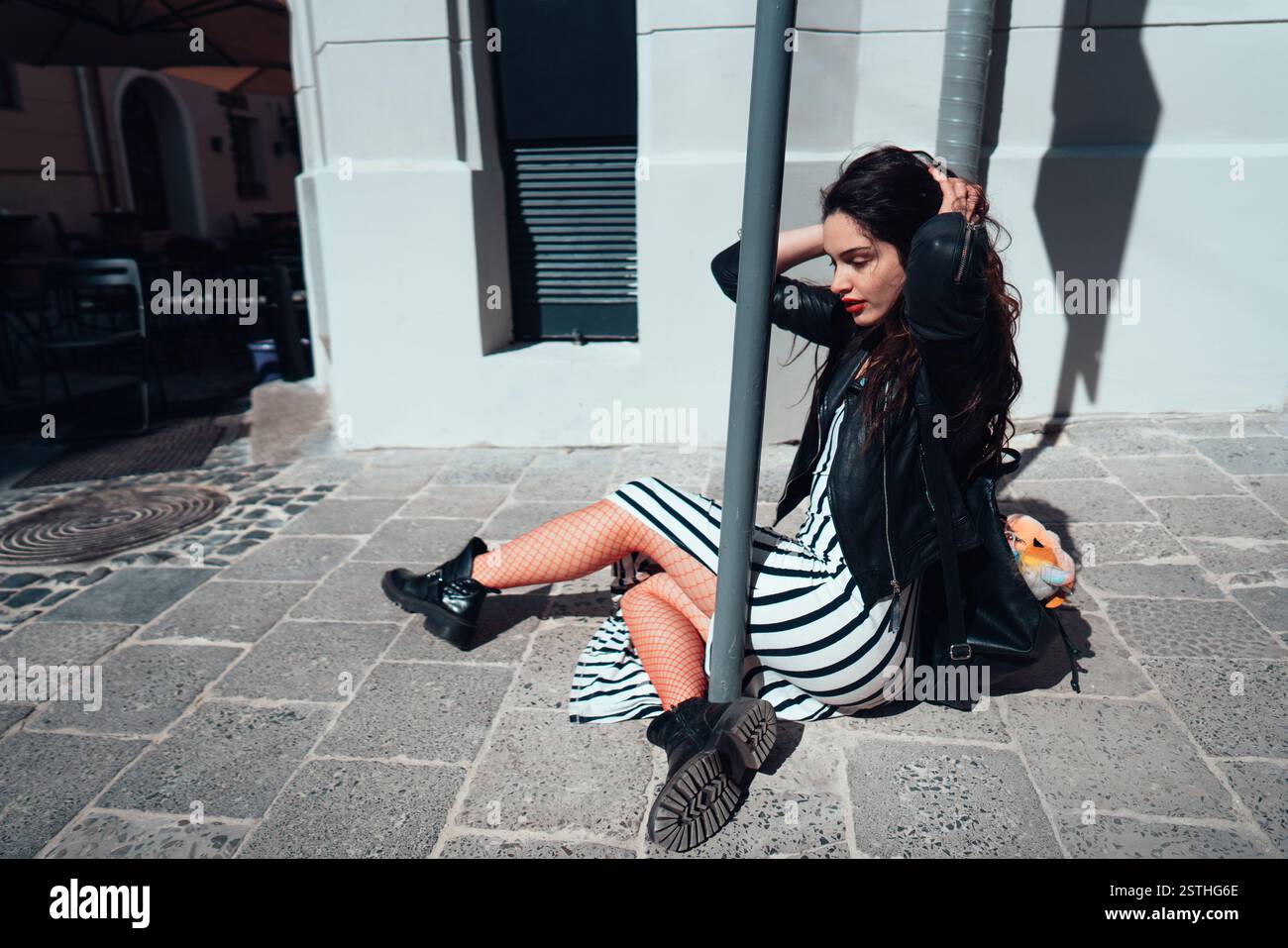 Beautiful fashionable lady sitting on old street Stock Photo