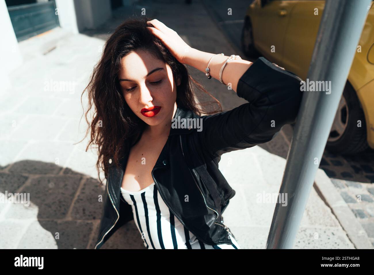 Beautiful fashionable lady sitting on old street Stock Photo