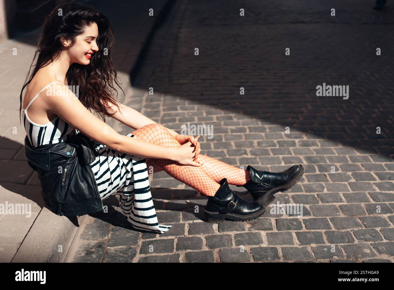 Beautiful fashionable lady sitting on old street Stock Photo