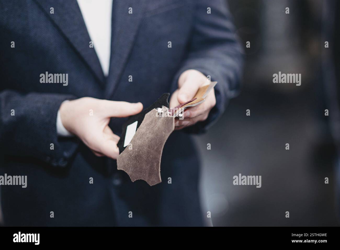 Man holding and examining leather material samples Stock Photo