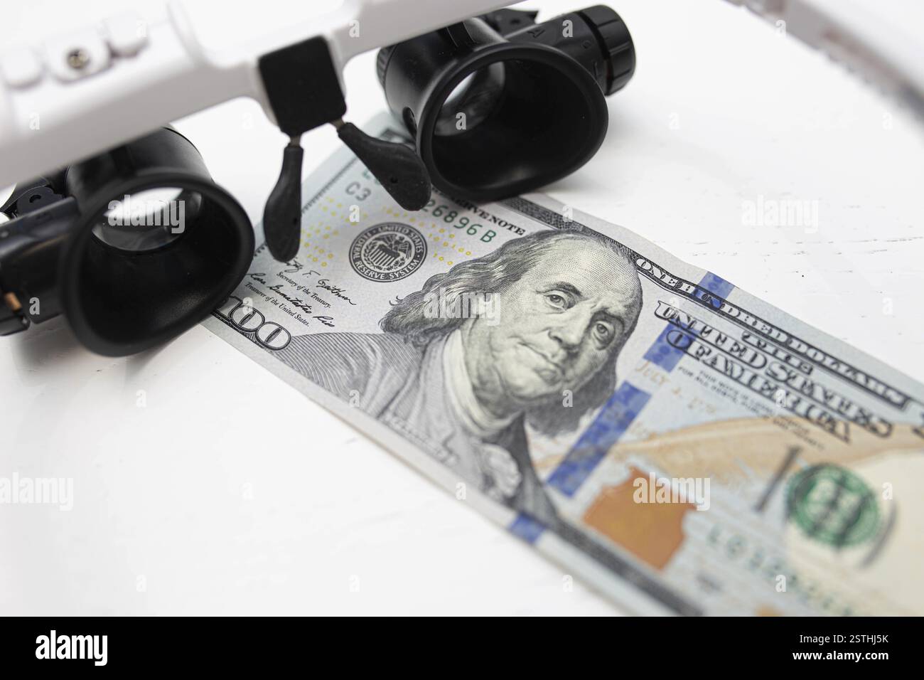 Magnifying glasses over a hundred dollar bill, highlighting financial ...