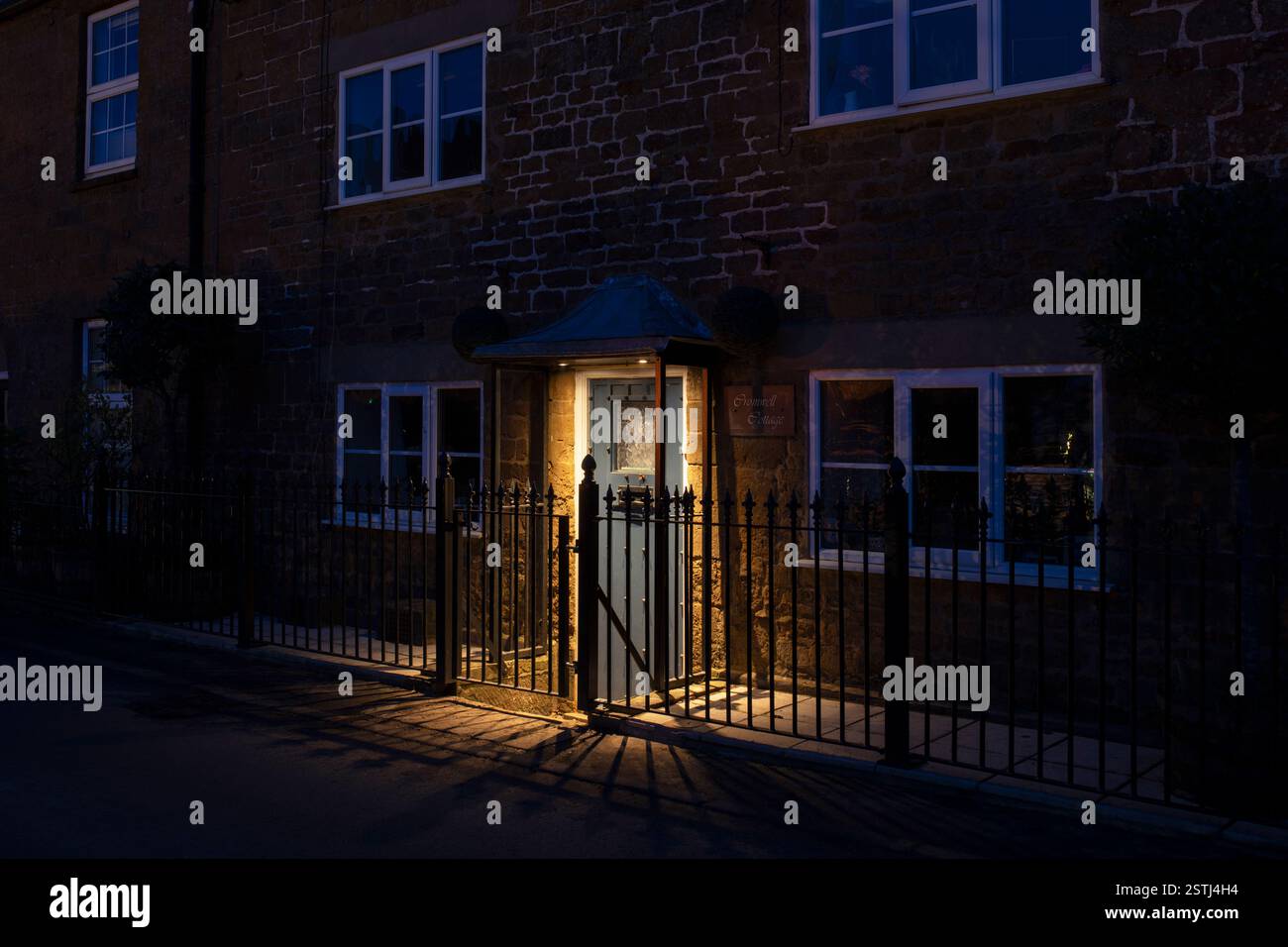 Illuminated front door at dusk casting shadows. Edgehill, Warwickshire, England Stock Photo